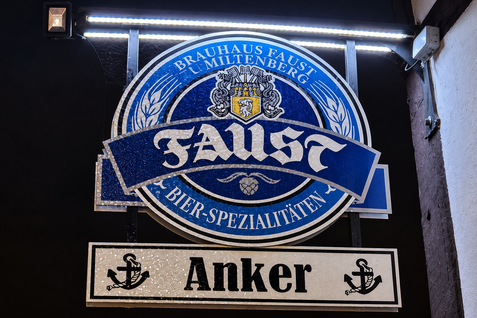 Beleuchtetes Faust- und Anker-Schild am Gasthaus bei Nacht